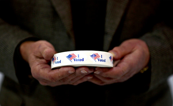 election official's hands hold voting stickers