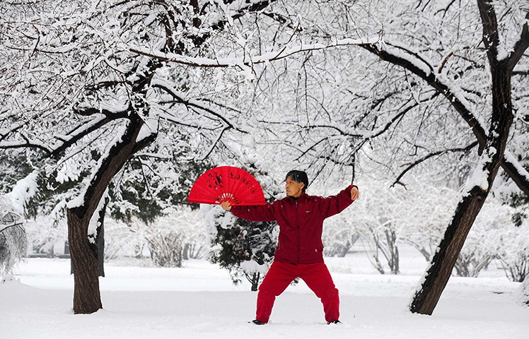 Shenyang, China: A woman practices tai chi with a fan after a snowfall